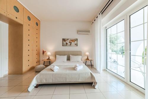 a bedroom with a large bed and large windows at Villa Noaina in Lagonissi in Lagonissi