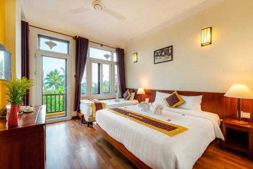 a hotel room with two beds and a large window at Hoi An Green Riverside Oasis Villa in Hoi An
