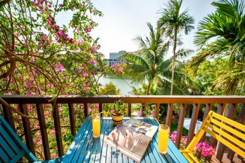 a blue table and chairs on a balcony with palm trees at Hoi An Green Riverside Oasis Villa in Hoi An