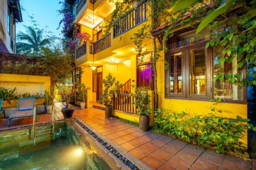 a yellow house with a pond in front of it at Hoi An Green Riverside Oasis Villa in Hoi An