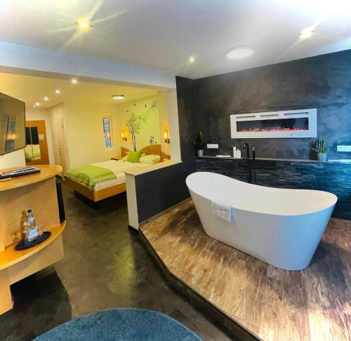 a bathroom with a bath tub and a bedroom at Berghotel Kristall in Idar-Oberstein