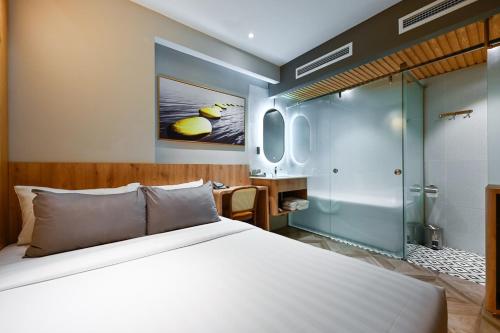 um quarto com uma cama grande e uma cabina de duche em vidro em La Opera Saigon Hotel em Cidade de Ho Chi Minh