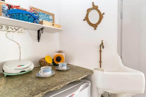 a bathroom with a sink and two cups on a counter at Apano Vrysi Tinos 3 in Tinos