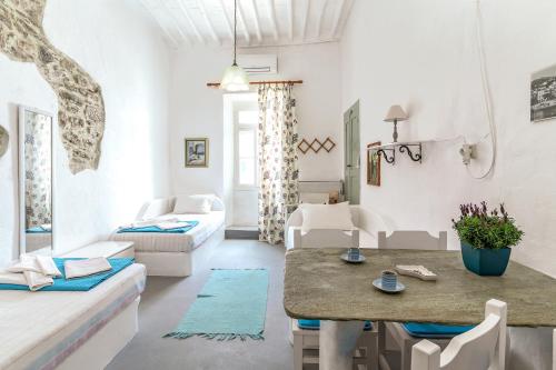 a white living room with a table and a couch at Apano Vrysi Tinos 3 in Tinos