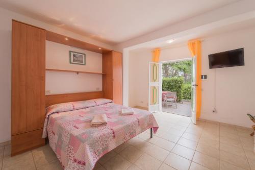 a bedroom with a bed and a television and a patio at Villino nel Bosco in Capoliveri