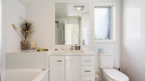 a white bathroom with a toilet and a sink at Krystal Peaks in Dinner Plain