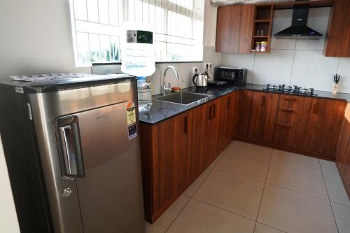 a kitchen with a stainless steel refrigerator and wooden cabinets at Kadampanattu's Homestay in Ernakulam