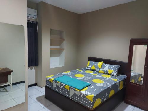 a bedroom with a bed with yellow and blue sheets at Penginapan Sriwijaya Semarang in Jomblang