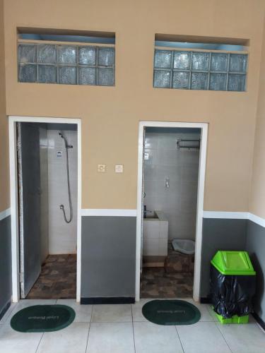 a bathroom with two doors with a shower and a toilet at Penginapan Sriwijaya Semarang in Jomblang