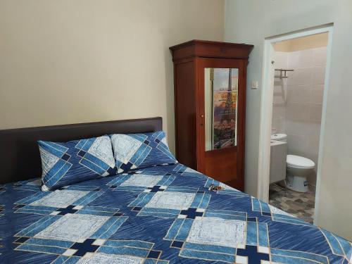 a bedroom with a bed with a blue comforter at Penginapan Sriwijaya Semarang in Jomblang