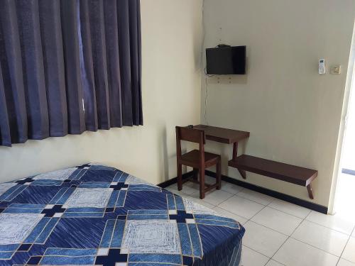 a bedroom with a bed and a desk and a television at Penginapan Sriwijaya Semarang in Jomblang
