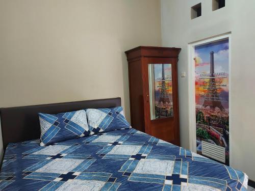 a bedroom with a bed with a blue and white comforter at Penginapan Sriwijaya Semarang in Jomblang