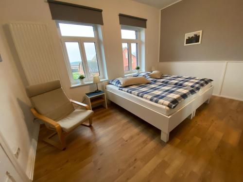 a bedroom with a bed and a chair and windows at Pension Grunwald in Sehnde