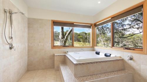 ein Bad mit einer Badewanne und einem Fenster in der Unterkunft Jasandre in Dinner Plain