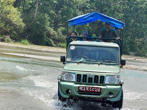 a group of people riding on the back of a jeep in the water at Hotel Rhinoceros-Homestay in Sauraha