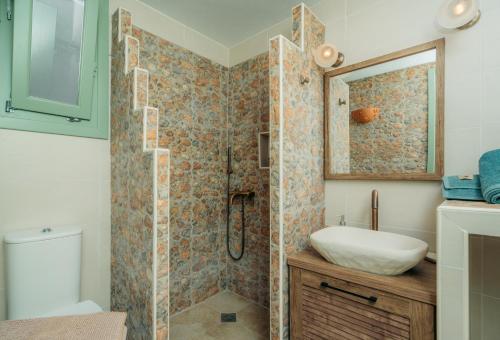 a bathroom with a shower with a sink and a mirror at Houses at Chrisopigi Sifnos in Chrisopigi