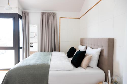 - une chambre avec un lit doté d'oreillers et d'une fenêtre dans l'établissement Moderne neue Apartments zum Wohlfühlen im Boardinghouse bed & butter, à Hasbergen