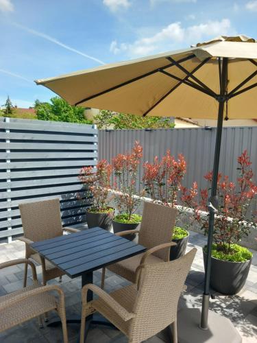 a table and chairs with an umbrella on a patio at Gemini Apartman in Esztergom