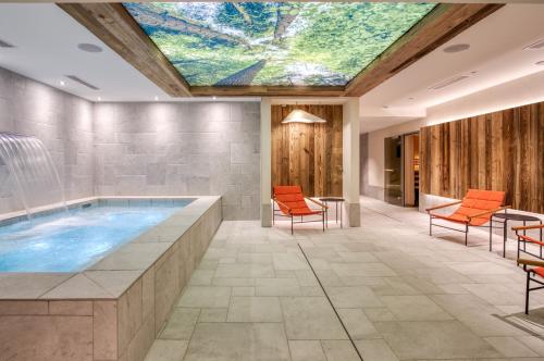 an indoor pool with a skylight and orange chairs at Chalet Hôtel Turquoise in La Plagne Tarentaise