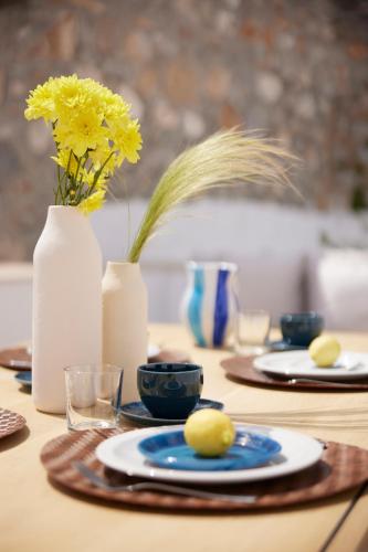 a table with plates and a vase with yellow flowers at Orloff Legacy Suites Hydra in Hydra
