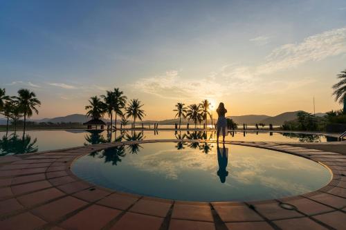 a woman standing in front of a swimming pool at Kaengkrachan Boathouse Paradise Resort in Kaeng Krachan
