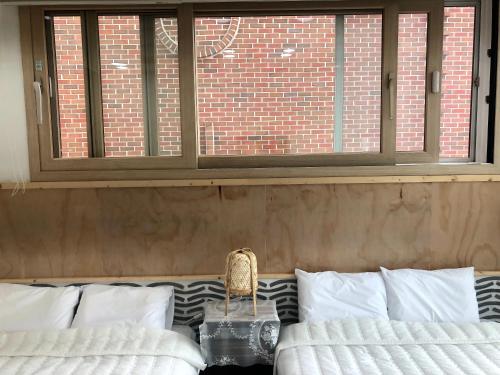 a room with two white beds and a window at Cheukhu-dong 19street Guesthouse in Mokpo