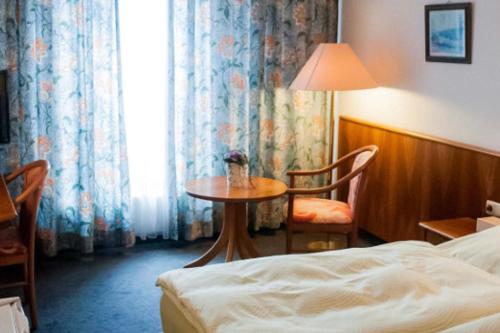 a hotel room with a bed and a table and a window at Hotel Stadt Steinbach in Steinbach im Taunus