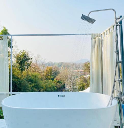 una vasca da bagno bianca di fronte a una finestra di La Maison Blanche Chiang Rai Resort a Chiang Rai