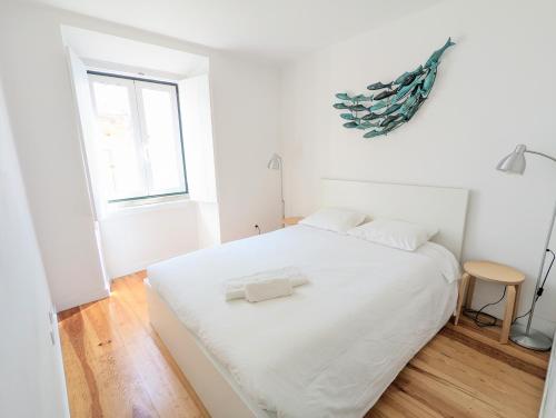 a white bedroom with a large bed with white sheets at Apartamentos Aurea in Sesimbra