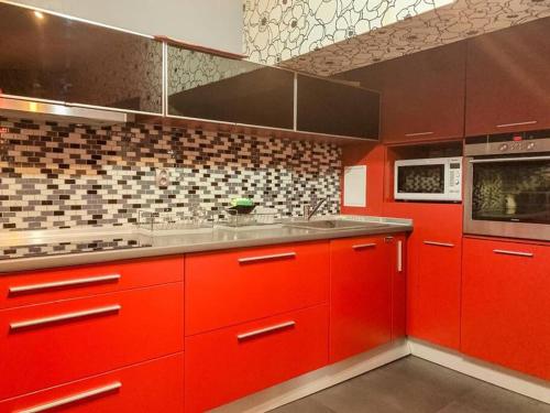 eine rote Küche mit roten Schränken und einem Waschbecken in der Unterkunft Aпартамент в близост до морето и центъра in Burgas City