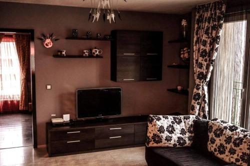 ein Wohnzimmer mit einem Sofa und einem Flachbild-TV in der Unterkunft Aпартамент в близост до морето и центъра in Burgas City