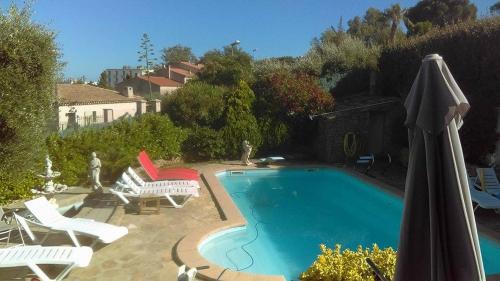 a swimming pool with two lawn chairs and an umbrella at Studio sur les hauteurs de La Ciotat vue mer in La Ciotat