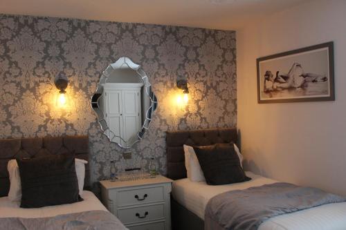 a bedroom with two beds and a mirror on the wall at The Mount Pleasant Hotel in Sidmouth