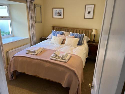 a bedroom with a bed with two towels on it at Woodbine Cottage in Tenby