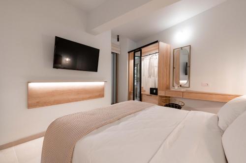 a bedroom with a bed and a television on the wall at Mariann Premium Suites in Lardos
