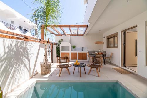 un patio al aire libre con piscina, mesa y sillas en Mariann Premium Suites, en Lardos