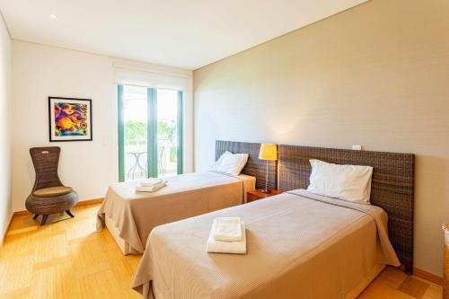 um quarto de hotel com duas camas e uma cadeira em Marina Vilamoura Aquamar 005 By Vilamoura Sun em Quarteira