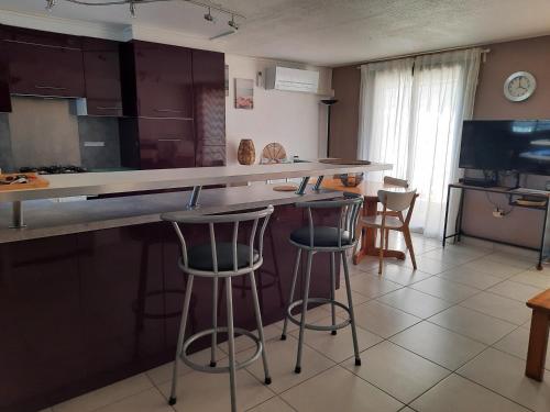 une cuisine avec deux tabourets de bar et un comptoir dans l'établissement Résidence les Sables D'or, au Cap d'Agde