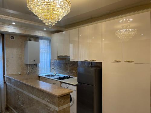 La cuisine est équipée de placards blancs et d'un réfrigérateur noir. dans l'établissement Avchieva's apartment on Pushkin street, à Erevan