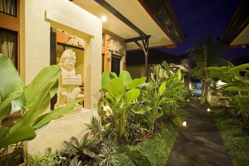 a garden with a statue on the side of a building at Natya Hotel Tanah Lot in Tanah Lot