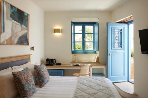 a bedroom with a bed and a desk and a window at Orloff Legacy Suites Hydra in Hydra