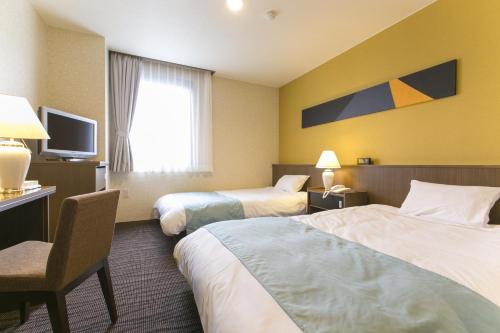 a hotel room with two beds and a television at Fujisan Station Hotel in Fujiyoshida
