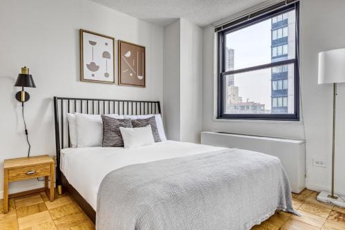 a white bedroom with a bed and a window at Murray Hill 1BR w Doorman Gym Pool Parking NYC-581 in New York