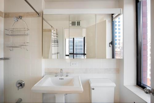 ein weißes Badezimmer mit Waschbecken und Spiegel in der Unterkunft Upper West Side 2br w gym nr Central Park NYC-1147 in New York
