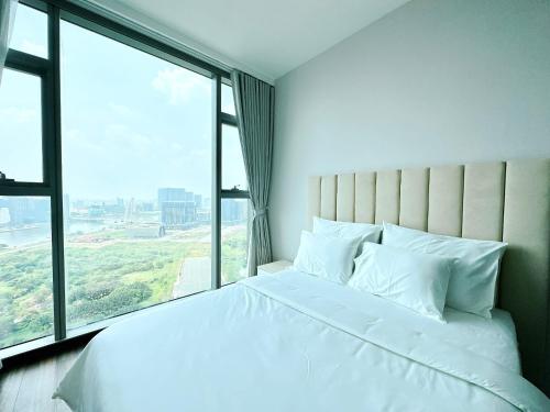 ein weißes Bett in einem Zimmer mit einem großen Fenster in der Unterkunft Empire city Thủ Thiêm Luxuriest Apartment Ho Chi Minh city Dist 2 in Ho-Chi-Minh-Stadt
