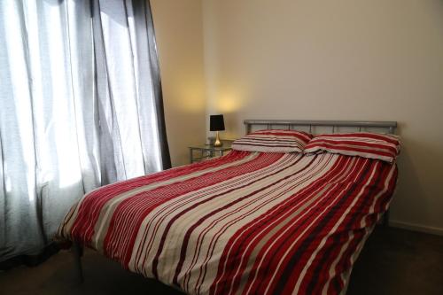 a bed with a red and white striped comforter in a bedroom at Apple House in Tarneit
