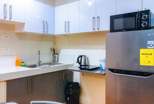a kitchen with a stainless steel refrigerator and white cabinets at Kara's Condotels in Cebu City