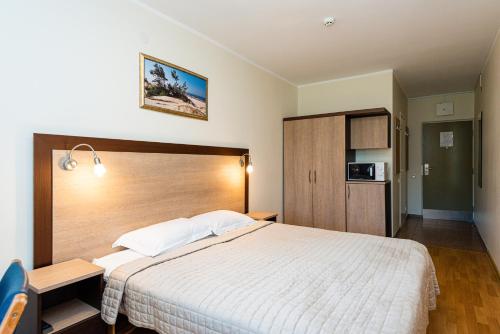 una camera da letto con un letto grande con testiera in legno di RR apartamentai Palangos centre a Palanga