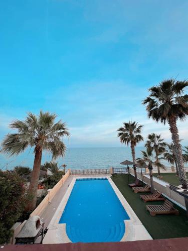 a swimming pool next to the ocean with palm trees at Oasi Rejuve Villa in Meneou