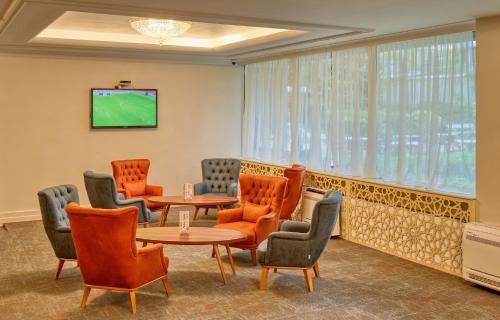 a waiting room with chairs and tables and a tv at Augusta SPA Hotel in Hisarya